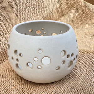 Ceramic holder with holes on a textured beige fabric background
