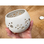 Load image into Gallery viewer, White ceramic holder with holes held in a hand against a textured beige background
